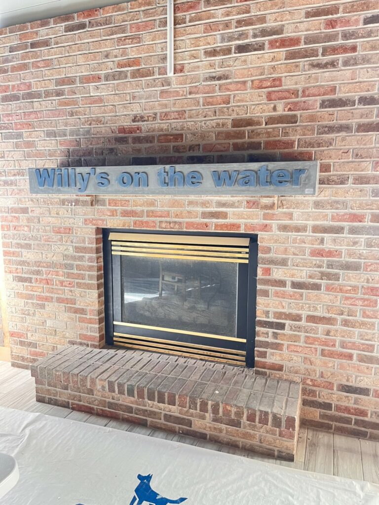 concrete fireplace mantel that says willy's on the water, fireplace hearth, hearth, mantel, mantle, fireplace mantel, fireplace mantle, fireplace surround, concrete fireplace, concrete, stone fireplace, luxury design, fireplace inspiration, fireplace inspo, interior design