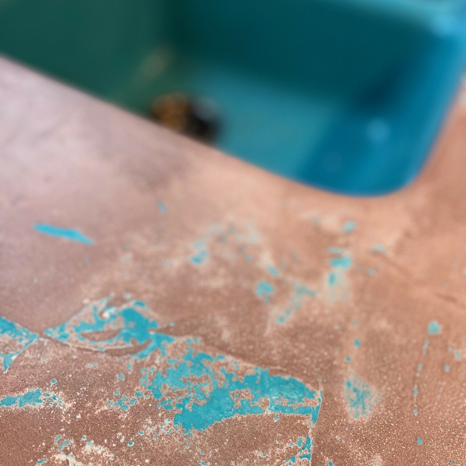 Close up view of concrete countertops that are a brownish red color with pops of teal blue
