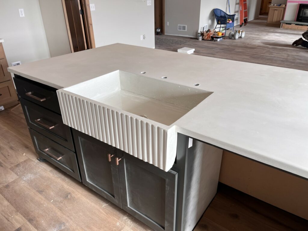 White concrete countertops with an integral fluted farmhouse sink